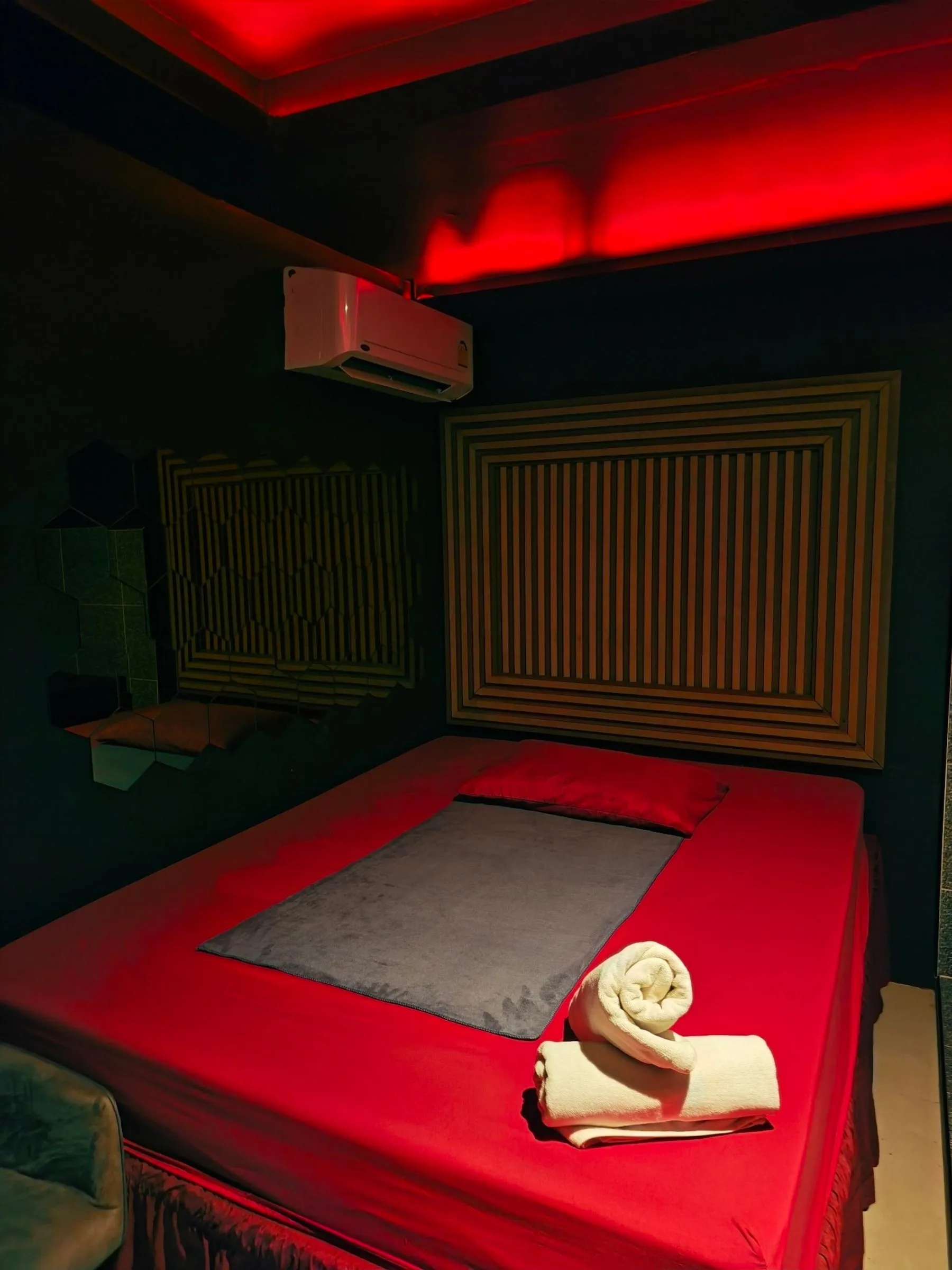 Amor 888のお部屋のベッド。赤いシーツの上に広げたグレーのタオルと、巻いたタオル2枚