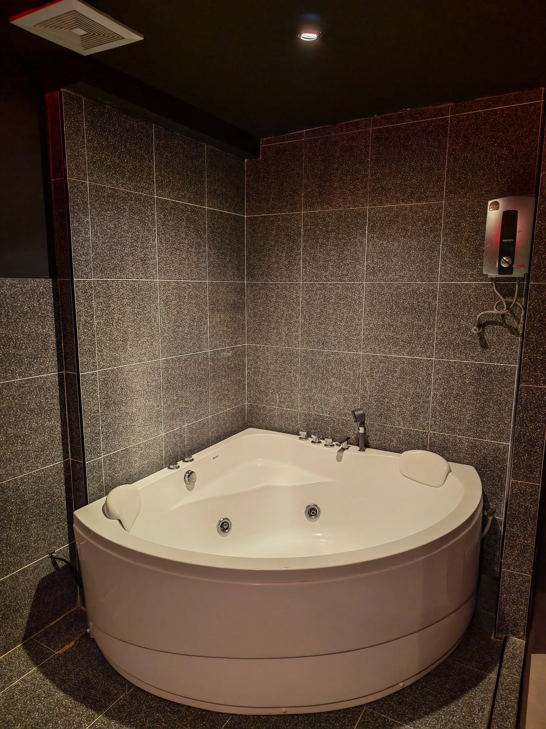 A white corner whirlpool bath in the tiled wet area of a room at Amor 888